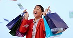 Woman, shopping bag and happy for money rain in studio with celebration, sale and deal by blue background. Japanese person, winner girl and cash shower with gift, dancing and giveaway with success