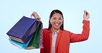 Asian woman, shopping bag and dance in studio with smile on face for deal by blue background. Japanese girl, discount and sale with celebration, excited or saving on gift, fashion or retail product