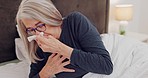 Senior woman blowing her nose in bed with tissues for sinus, allergies or flu in her home. Medical, recovery and elderly female patient in retirement resting with cold or sickness in her modern house