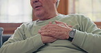Hands, heart attack or condition with a senior man in pain closeup in the living room of his retirement home. Healthcare, chest or cardiac arrest with an elderly person breathing for lung oxygen