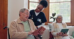 Senior man, reading and nurse talking in home with book, discussion or support from nursing staff. Retirement, elderly care or person relax in conversation with caregiver in living room with notebook