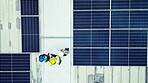 Overhead, solar power and an engineering team on the roof of a building to install panel technology. Construction, electricity and renewable energy with people working on a sustainability project