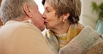 Love, retirement and senior couple kissing on a sofa in the living room of their home together for romance. Smile, relax or hug with an elderly man and woman embracing for affection in their house