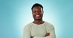 Face, black man and smile in studio with arms crossed, good mood and happy personality on blue background in Nigeria. Portrait, confident model and laugh for pride, freedom and funny reaction to joke