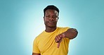 Thumbs down, face or man in studio for sad rejection of bad news, emoji sign or no feedback on blue background. Portrait, african model and negative review, wrong decision or vote for icon of failure