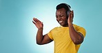 Happy black man, headphones and listening to music, podcast or playlist against a studio or blue background. African male person smile, dancing and enjoying audio streaming or sound track on mockup