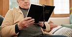 Religion, reading and senior man with a bible on sofa in the living room for spiritual wellness. Peace, gratitude and elderly male person in retirement studying holy christian book in lounge at home.