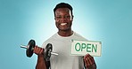 Happy black man, dumbbell and open sign for gym, fitness or motivation against a blue background. Portrait of active African male person smile for weightlifting, workout or exercise with billboard