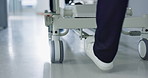 Healthcare, doctor and push bed in hospital for surgery, emergency or medical problem in corridor. Medicine, professional and nurse feet with stretcher for wellness, service and risk in clinic or job