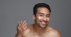 Face, cream and man with skincare, dermatology and beauty with glow on a grey studio background. Portrait, person and model with creme, smooth and luxury treatment with grooming, shine and aesthetic