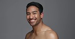 Face, funny and Asian man with beauty, skincare and dermatology on a grey studio background. Portrait, Japanese person and model with wellness, laughing and cosmetics with aesthetic, shine and glow