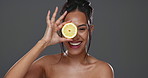 Face, skincare and happy woman with lemon for beauty in studio isolated on gray background. Portrait, natural fruits and food of model for cosmetics, healthy diet and nutrition for organic vitamin c