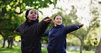 Interracial women, fitness and pilates in nature for workout, exercise or training together. Female person, friends or personal trainer in yoga, warrior pose or coaching at park in spiritual wellness