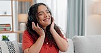 Happy woman, headphones and listening to music on sofa for weekend or relax in living room at home. Female person smile enjoying sound track, songs or podcast for audio streaming in lounge at house