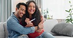 Love, surprise and pregnancy test with a couple hugging on a sofa in the living room of their home in celebration. Family, smile or excited with a happy man and woman embracing for good news