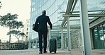 Suitcase, travel and businessman walking in the city for corporate work trip by airport. Luggage, building and back of professional male person with bag for company flight at hotel in urban town.