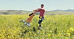 Playing, man and child in field of flowers bonding and spinning in grass in nature together. Love, playful father and daughter in countryside for outdoor summer holiday fun, freedom and adventure. 