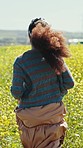 Woman running, flower and farm field closeup on adventure, travel and summer in countryside in grass. Vacation, walking and freedom on holiday with plants and nature with back and sunshine on trip