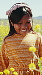 Happy child, flower and field closeup on adventure, travel and summer in countryside in grass. Vacation, walking and freedom on holiday with smile and nature with calm kid and sunshine on trip