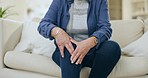 Knee pain, hands and senior woman on a sofa with arthritis, osteoporosis or inflammation at home. Leg, injury and zoom of elderly female with muscle or joint crisis in a living room with fibromyalgia