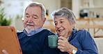 Coffee, tablet and senior couple on a sofa talking, relaxing and networking on social media together. Happy, digital technology and elderly man and woman in retirement scroll on mobile app at home.