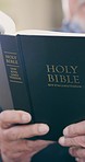 Closeup, hand and bible for reading with worship, scripture or prayer for church, religion and spirituality. Elderly person, man and book of God for learning, faith and study for wellness of soul