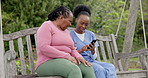 Senior, woman and caregiver with phone in nature with communication for memory loss, dementia or alzheimer. Elderly, black people and nurse with smartphone on swing with pictures to remember or doubt