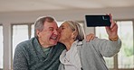 Phone, kiss and senior couple with selfie in a living room with care, trust and support at home. Smartphone, profile picture and old people in a house with love, fun and retirement, freedom or bond