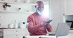 Phone, laptop and budget with a senior black man in the kitchen of his home for finance planning. Mobile, computer and investment with an elderly person reading information for retirement savings