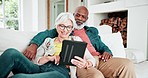 Senior couple on sofa with tablet, smile and relax with love, interracial marriage and bonding in home. Social media meme, digital app and happy people, old man and woman on couch in living room.