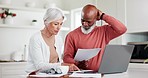 Senior couple, documents and laptop in financial crisis, debt or expenses and bills in kitchen at home. Mature woman and man with paperwork in budget planning, finance or review together at house