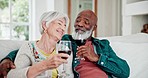 Love, diversity and wine with a senior couple drinking alcohol on a sofa in the living room of their home together. Smile, romance or bonding with a happy elderly man and woman in their apartment