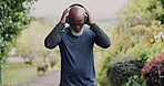 Nature, headphones and senior black man running at park, garden or outdoor. Listening to music, cardio and African athlete exercise, training or workout for healthy body, wellness and sport fitness