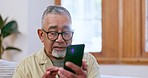 Senior man, phone text and home with retirement and living room with social media app on sofa. Mobile networking, elderly male person and website with online message in a lounge reading a post