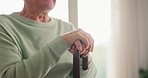 Closeup, hands and elderly man with a cane with disability in home for support, rehabilitation or sick in retirement. Health, lonely person and aid of walking stick for parkinson, care and arthritis