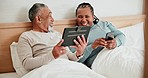 Phone, tablet and mature couple in bed, typing and conversation together in the morning. Technology, happy man and interracial woman in bedroom on internet, social media or digital mobile app at home