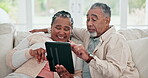 Happy, interracial couple and a tablet on the sofa for a website, reading email or an app. Laughing, home and an black woman with a man, talking and connection from technology for the internet