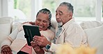 Happy, interracial couple and a tablet on the sofa for reading an email or story on an app. Laughing, home and a black woman with a man, talking and connection from technology for the internet