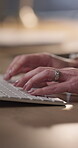 Hands, typing and keyboard with a person closeup in an office to work on a report or project. Computer, internet or research at a desk in the workplace with an employee working in the evening