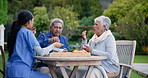 Talking, garden and a nurse with a couple for breakfast, conversation and coffee together. Happy, table and a female caregiver with lunch, food or tea with an elderly man and woman in nature