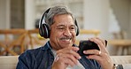 Laughing, senior man and a video on a phone, watching a movie or film on the internet. Happy, streaming and an elderly person with headphones, mobile and a comedy show on an app on the home sofa