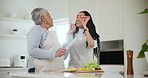 Family, cooking or toast with an old woman and daughter in the kitchen of a home during a visit. Eating, smile or happy and a young person laughing with her senior mother in a house to prepare a meal