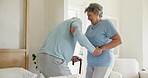 Senior man, woman and bed with walking stick, help and care in morning with trust, patient or support. Couple, bedroom and elderly person with disability, rehabilitation or recovery with lady in home
