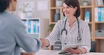 Medicine, tablet and doctor shaking hands with a patient in the office of a hospital for medical agreement. Handshake, welcome or thank you with a healthcare professional meeting a woman in a clinic