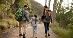 Happy family, hiking and holding hands outdoor, backpack and care in nature. Mother, father and kid trekking in forest, walk in woods and travel together on vacation, holiday or bonding on adventure