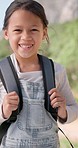 Happy, face and child on a hike with backpack in nature on a mountain for outdoor travel holiday. Smile, excited and portrait of girl kid on an adventure, vacation or weekend trip in countryside.