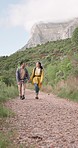 Smile, couple holding hands and hiking in nature, travel and talking together outdoor. Happy, man and woman trekking in countryside on journey, adventure and walking for freedom, love and support