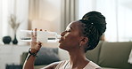 Fitness, black woman and drinking water in bottle in home, healthy diet or wellness. African athlete, thirsty or liquid for hydration after workout, sport training or exercise to relax in living room