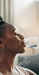 Break, fitness and black woman drinking water in a house from a bottle from training or for clean diet. Healthy, sports and an African girl with a drink for nutrition, exercise or relax after workout