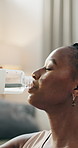 Thirsty, fitness and black woman drinking water in a house on a break from training or for clean diet. Healthy, sports and an African girl with a drink for nutrition, exercise or relax after workout